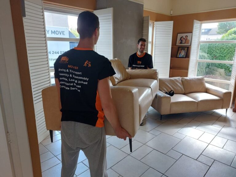 Professional movers from The Easy Move carrying a sofa with a smile, making relocations easy in Weert.